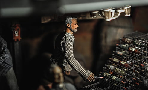 Selective Focus Photography of Male Doll Holding Bottle Near Bottle Rack thumbnail