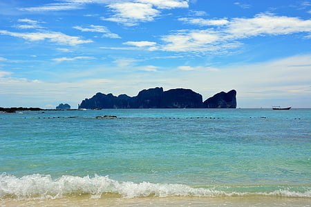 sea near mountain under white clouds during daytime thumbnail