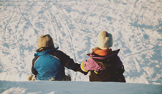 two person sitting on snow during daytime thumbnail