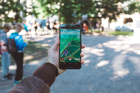 person holding smartphone while playing Pokemon Go thumbnail