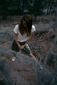 woman standing on brown soil looking downwards thumbnail