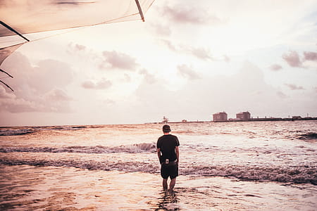 A young caucasian man wading in sea water on the beach thumbnail