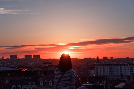 woman in white and black striped standing in front of sunset thumbnail
