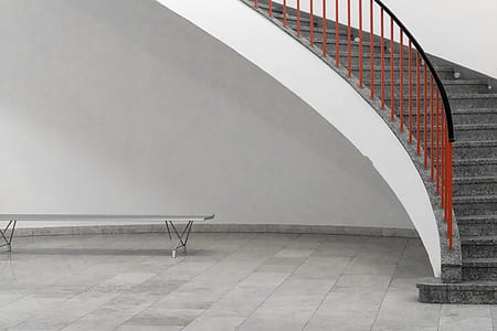 gray concrete stair with red and black metal railing inside lighted room thumbnail