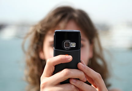 selective focus photography of woman holding phone thumbnail
