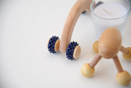 two brown massagers beside white votive candle thumbnail