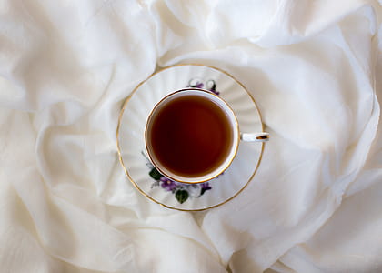 white teacup with tea placed on white textile thumbnail
