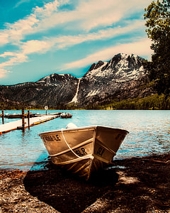 brown canoe boat against body of water and mountain thumbnail