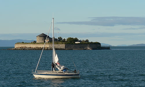 white sail boat on water beside island thumbnail