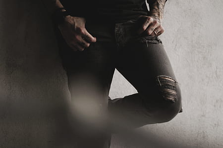 person wearing distressed black jeans leaning on wall thumbnail