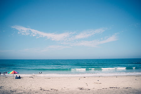 people sitting under parasol near shore during daytime thumbnail