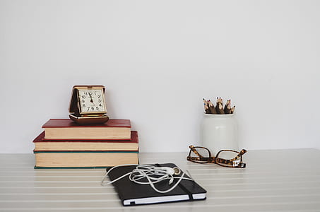 books placed on table beside eyeglasses and pencil case thumbnail