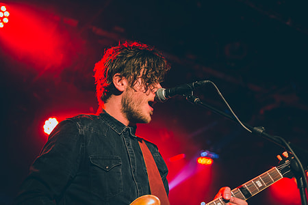 man playing guitar while singing on stage thumbnail