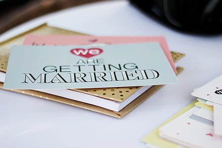 we are getting married invitation card on top of yellow book thumbnail