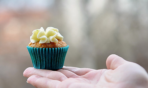 selective focus photography of person holding cupcake thumbnail
