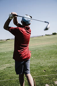 Man Swinging Golf Club Facing Grass Field thumbnail