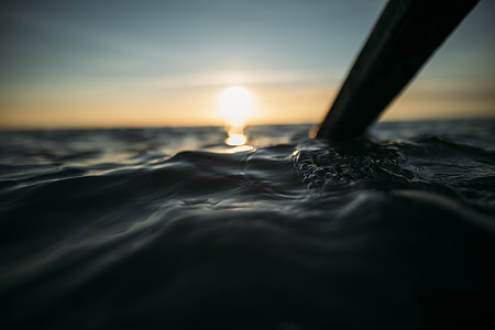 selective focus photography of brown paddle underwater during golden hour thumbnail