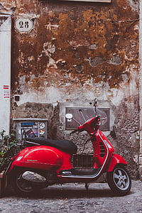 red motor scooter parked near wall thumbnail
