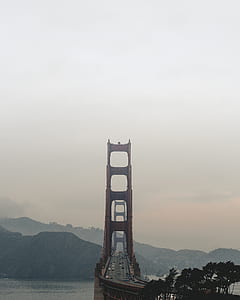 brown bridge over calm body of water across hills thumbnail