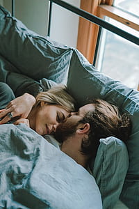 man kissing woman in forehead while lying in bed thumbnail
