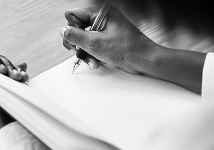 person writing on paper in grayscale photography thumbnail