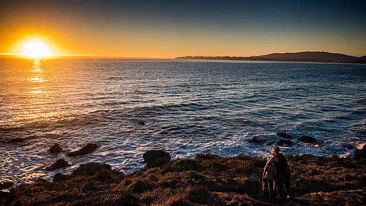 people watching sunset on rocky shore thumbnail