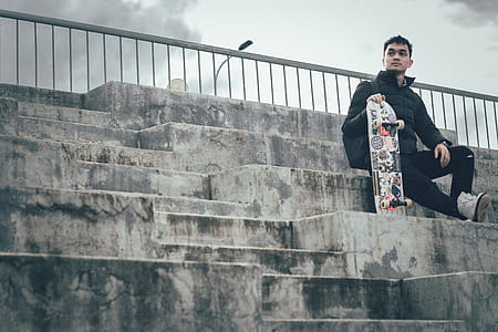 Man Holding Skateboard Sitting On Stairs thumbnail