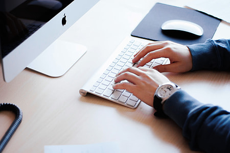 Man’s hands typing on computer keyboard on office desktop thumbnail