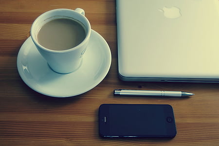 white ceramic cup filled with coffee on white saucer near silver MacBook thumbnail