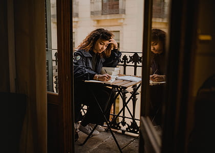 woman studying in veranda during daytime thumbnail