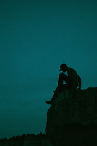 silhouette of man sitting on stone during nighttime thumbnail