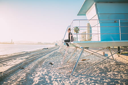 candid photography of woman sitting at beach kiosk under golden hour thumbnail