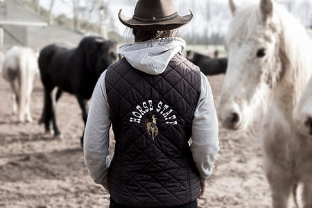 person wearing gray and black Horse Staff print jacket and black leather cowboy hat thumbnail
