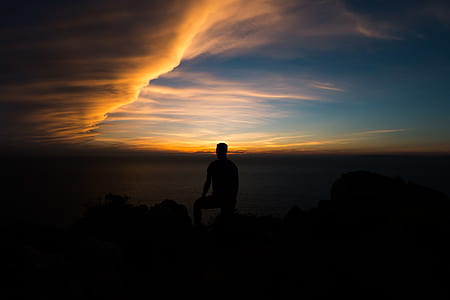 silhouette photo of man standing on peak surface during sunset thumbnail