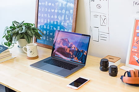 MacBook Pro on brown wooden table near two black camera lenses thumbnail