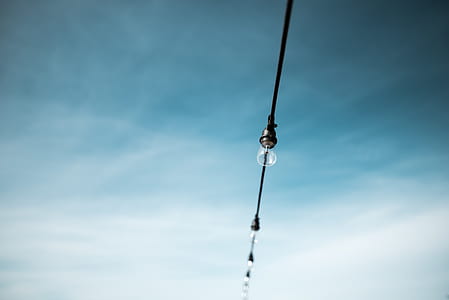 focus photography of clear LED bulb on string under white and white sky at daytime thumbnail