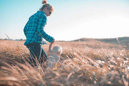 selective focus photography of woman holding hand of baby walking on grass field thumbnail