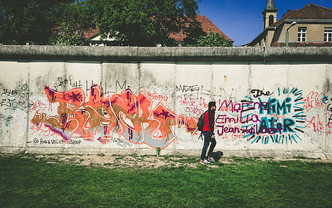 man walks beside wall with paintings thumbnail