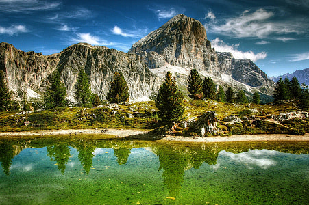 body of water near trees in front of mountain below clear sky during time thumbnail