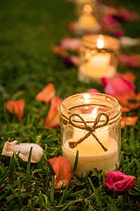 selective focus photography of votive candle on clear glass jar thumbnail