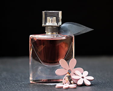 fragrance bottle beside three pink petaled flowers thumbnail