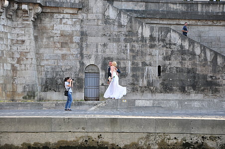 woman taking photo of couple beside gray wall thumbnail