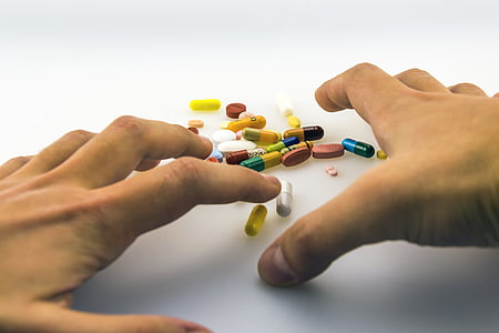 human hand with assorted medication pill on table thumbnail