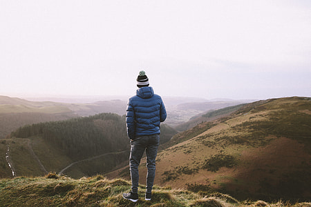 person in blue jacket standing on brown mountain at daytime thumbnail