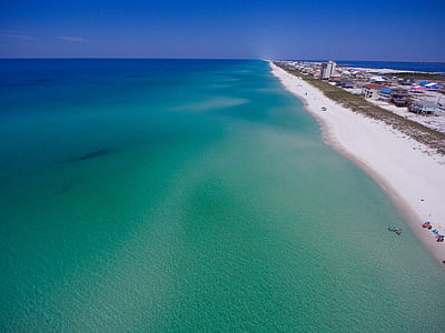 white sand beach near body of water under blue sky at daytime thumbnail