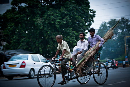 three men riding bike on road thumbnail
