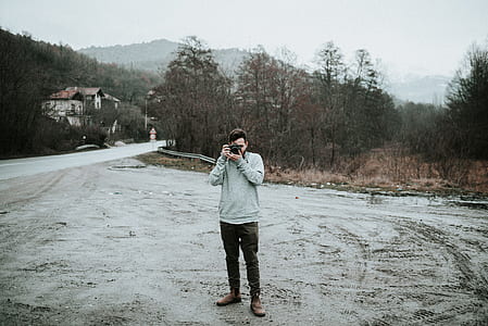 man standing on gray surface while holding camera thumbnail