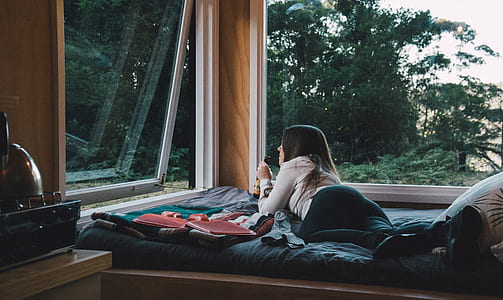 woman lying on bed while holding bottle thumbnail
