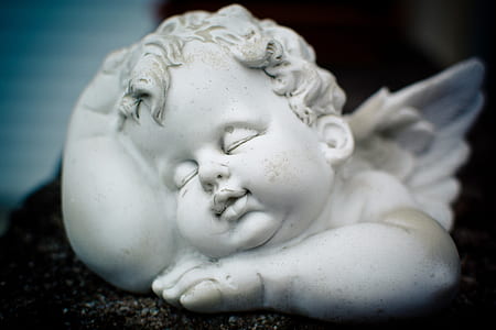 selective focus photography of sleeping cherub statuette thumbnail