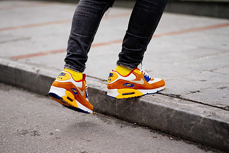 person wearing yellow-white-and-orange Nike Air Max 90 shoes thumbnail
